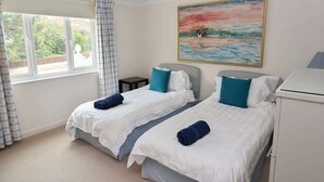 Habitación de hotel con dos camas, un cuadro en la pared y una ventana con cortinas.