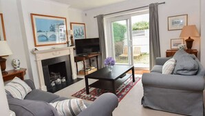 Una sala de estar con chimenea, sofá, televisión y vistas al exterior.