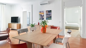 A modern dining area with a wooden table, chairs, a television, and artwork on the walls.