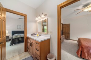 A bathroom with a white sink, wooden cabinets, a mirror, and a ceiling fan.