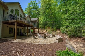 A covered patio area with Adirondack chairs and a stone fire pit.