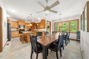 A modern kitchen with wooden cabinets, a central island, and a dining area with chairs.