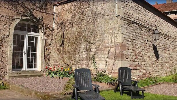 A stone building with a large arched window and two black chairs in front. - JOSEPHINE BEDROOM  (Luxeuil-les-Bains)