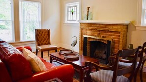 A living room with a brick fireplace, a red sofa, and a wooden coffee table.