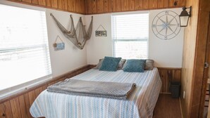 Ein Schlafzimmer mit einem Bett, einem Fenster, einer Wandlampe und einer Kompassdekoration.