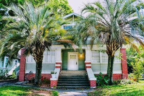 A two-story house with a front porch, surrounded by palm trees. - Montrose Place #4 Sum (Houston)