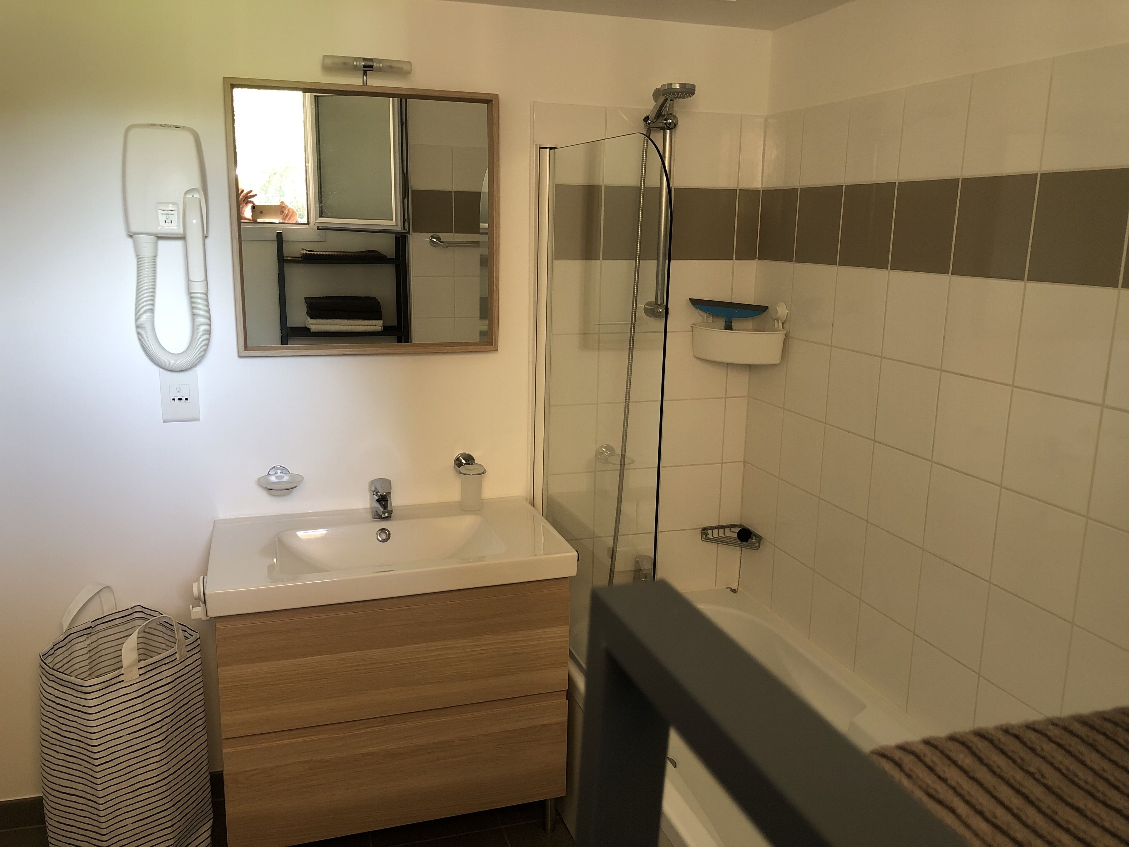 A bathroom with a sink, mirror, and shower.