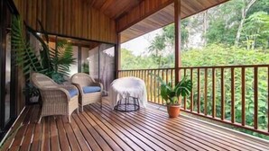 Eine Holzterrasse mit Korbmöbeln und einem Blumentopf.