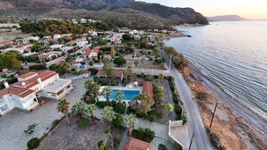 A coastal residential area with houses, a swimming pool, and a road leading to the beach. - Villa Supreme (Megara)
