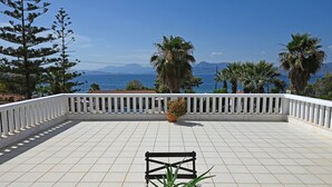A terrace with a white railing, a table, and a potted plant. - Villa Supreme (Megara)