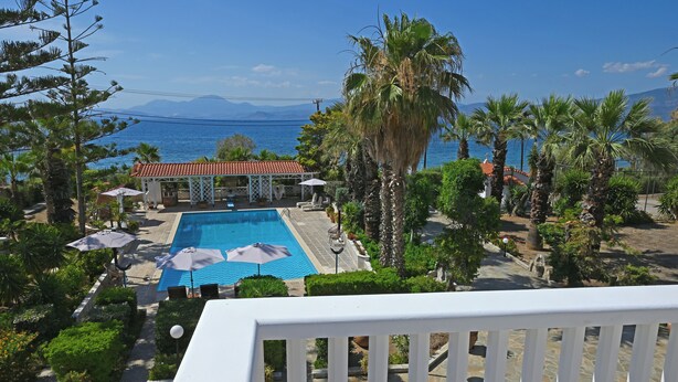 A pool area with umbrellas, palm trees, and a view of the sea. - Villa Supreme (Megara)