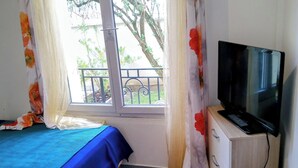 A bedroom with a bed, a television on a wooden cabinet, and a window with curtains. - Apartment with garden near Maisons-Alfort veterinary school, metro 8 (Maisons-Alfort)