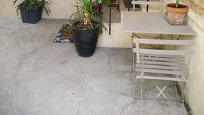 A small outdoor area with a concrete floor, potted plants, a metal table, and a staircase. - Apartment with garden near Maisons-Alfort veterinary school, metro 8 (Maisons-Alfort)