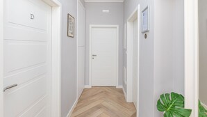 Un passadís amb portes blanques, un quadre al mur i una planta en test.