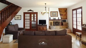 Un ampio soggiorno con una scala in legno, un camino e un televisore.
