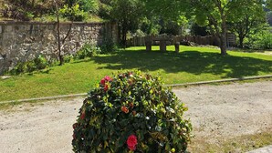 Un giardino con un muro di pietra, erba verde e alberi.