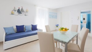 A modern living room with a sofa, dining table, and chairs. There is a painting on the wall and a window with curtains. - SeaView Sorrento Apartment by the sea with terrace  (Sorrento)