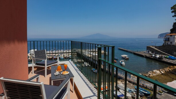 A balcony with a view of the sea, a dock with boats, and a mountain in the distance. - SeaView Sorrento Apartment by the sea with terrace  (Sorrento)
