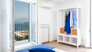 A bedroom with a balcony, a white wardrobe, and a bed with blue bedding. - SeaView Sorrento Apartment by the sea with terrace  (Sorrento)