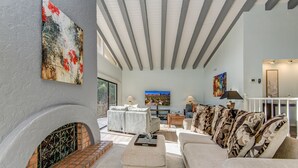 A living room with a fireplace, a large TV, and a sofa with patterned cushions.