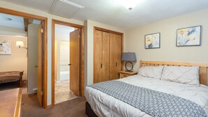A bedroom with a bed, a nightstand, a lamp, a wardrobe, and a door leading to another room. - Evergreen B5 (Brian Head)