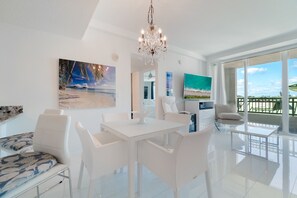 Un soggiorno moderno con un tavolo da pranzo bianco, un lampadario e opere d'arte alle pareti.