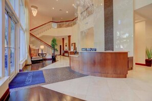 Un'ampia hall con una reception, una scala e un lampadario.