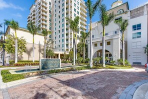 Un hotel con un cortile centrale, palme e un cartello con i numeri delle camere 350, 400 e 450.
