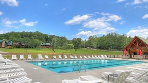 A swimming pool with lounge chairs and a wooden structure with red accents.