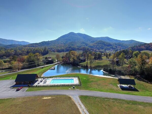 A swimming pool surrounded by a grassy area with a mountain in the background.