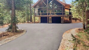 Un bâtiment moderne doté d’un grand garage et d’un espace extérieur abrité, le tout entouré d’arbres.