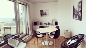 A modern living room with a round table, black chairs, a sofa, and a view of the sea through large windows. - NICE TWO-BEDROOM APPARTMENT WITH TERRACE (Oostende)