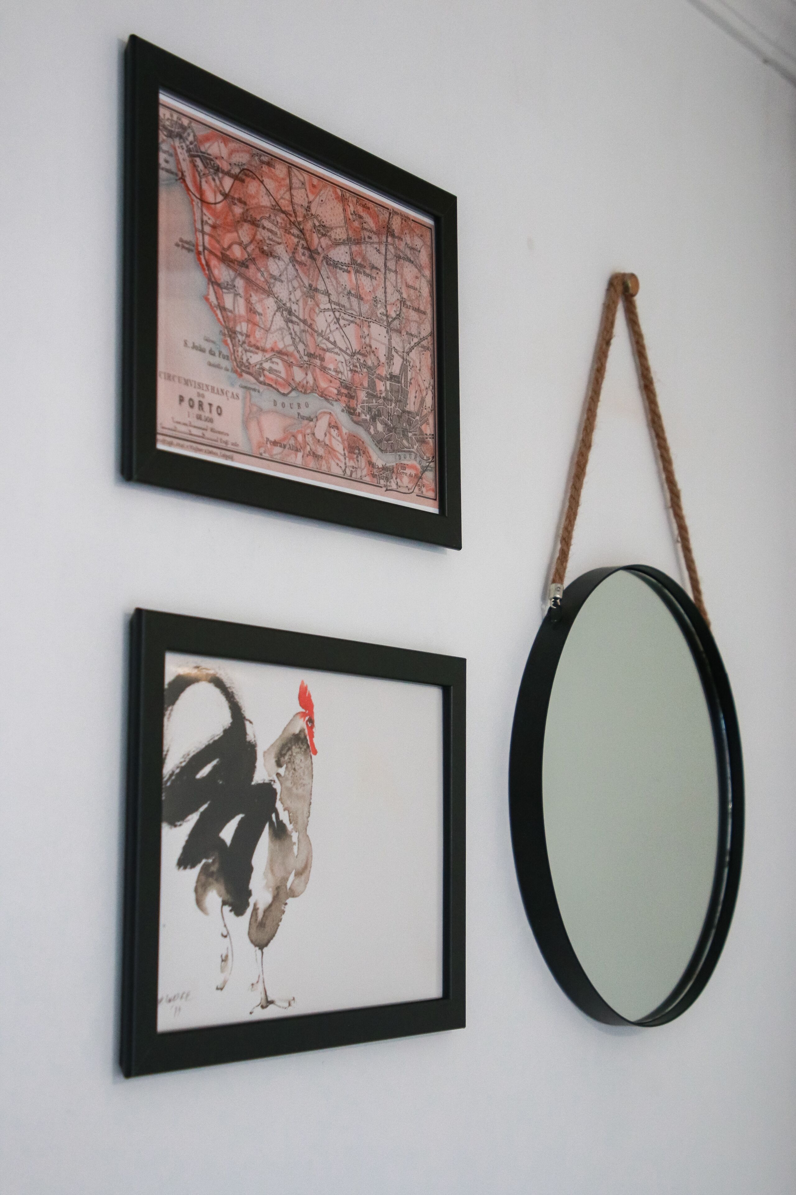 Two framed artworks and a mirror on a wall.