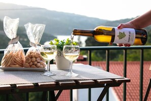 A table with snacks, glasses, and a bottle of wine being poured, set against a scenic outdoor backdrop. - Regouro - an Hidden Gem in Douro Valley (Cinfães)
