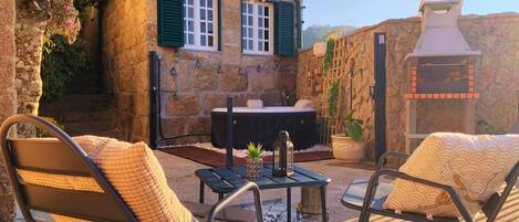 Un edificio de piedra con jacuzzi, mobiliario exterior y chimenea.
