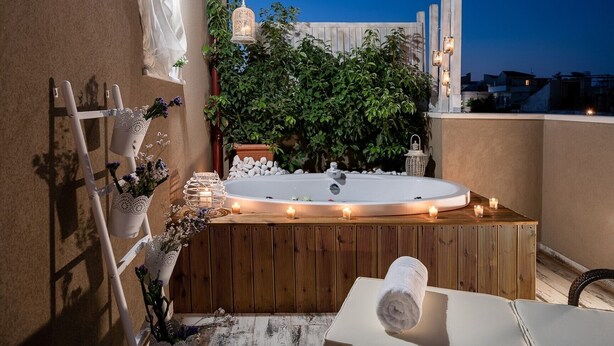 Un jacuzzi sur le toit, avec une terrasse en bois, entouré de plantes en pot et de bougies.