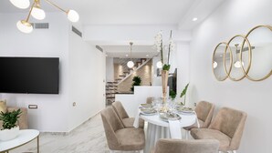 Un espace repas moderne avec une table ronde pour quatre personnes, des chaises à revêtement beige et une nappe blanche.