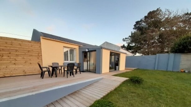 A modern house with a wooden deck, a small outdoor seating area, and a well-maintained lawn. - LA GABARDISE (Plouarzel)