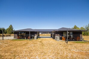 A modern outdoor structure with two covered areas, each featuring a barbecue grill and seating.