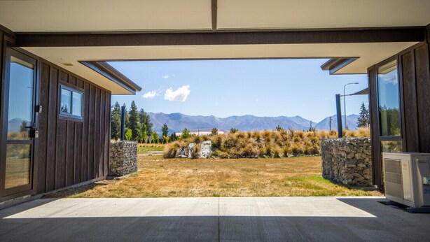 Un bâtiment moderne doté de grandes portes vitrées et offrant une vue sur les montagnes.