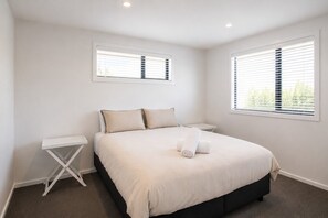 A bedroom with a bed, two bedside tables, and two windows with blinds. - Tussock Treasure - Exclusive Use (Twizel)