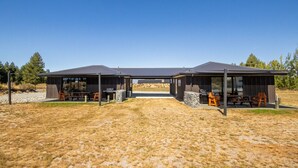 Une structure extérieure moderne dotée de deux espaces abrités, chacun comprenant un barbecue et des sièges.