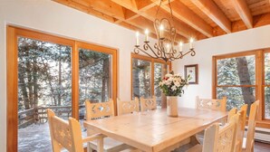 A wooden dining table with six chairs, a chandelier, and a vase of flowers. - RAVEN WOOD, 400 FT TO SKI RUNS, HOT TUB, SAUNA, PRIVATE (Sundance)