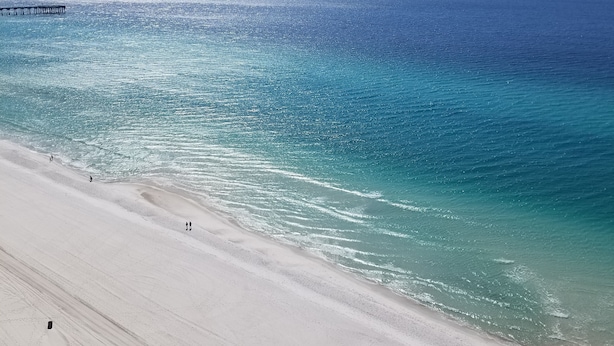 A beach with a pier extending into the ocean.