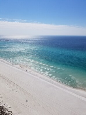 A beach with a pier extending into the ocean. - Beachfront Oasis Plus Romantic Sunsets! (Panama City Beach)