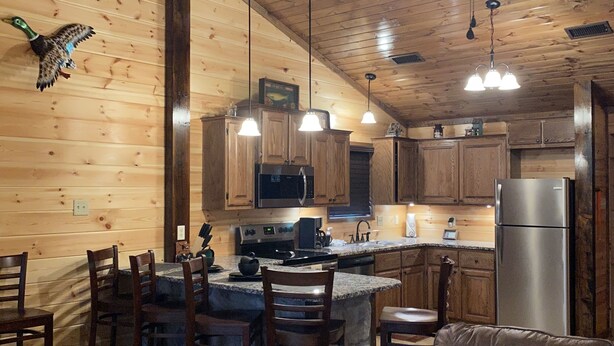 L’intérieur d’un chalet en bois comprend une cuisine, un coin repas et un espace de vie chaleureux.