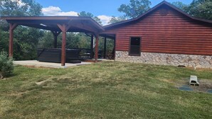 Une cabane en bois rustique, dotée d’un patio couvert et de fondations en pierre.