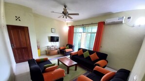 A living room with a sofa set, a coffee table, a TV, and a ceiling fan.