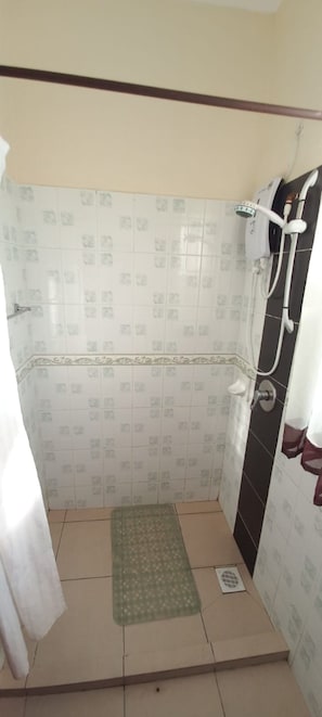 A shower area with tiled walls, a showerhead, and a drain.