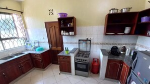 A kitchen with a gas stove, oven, refrigerator, and various kitchen utensils.